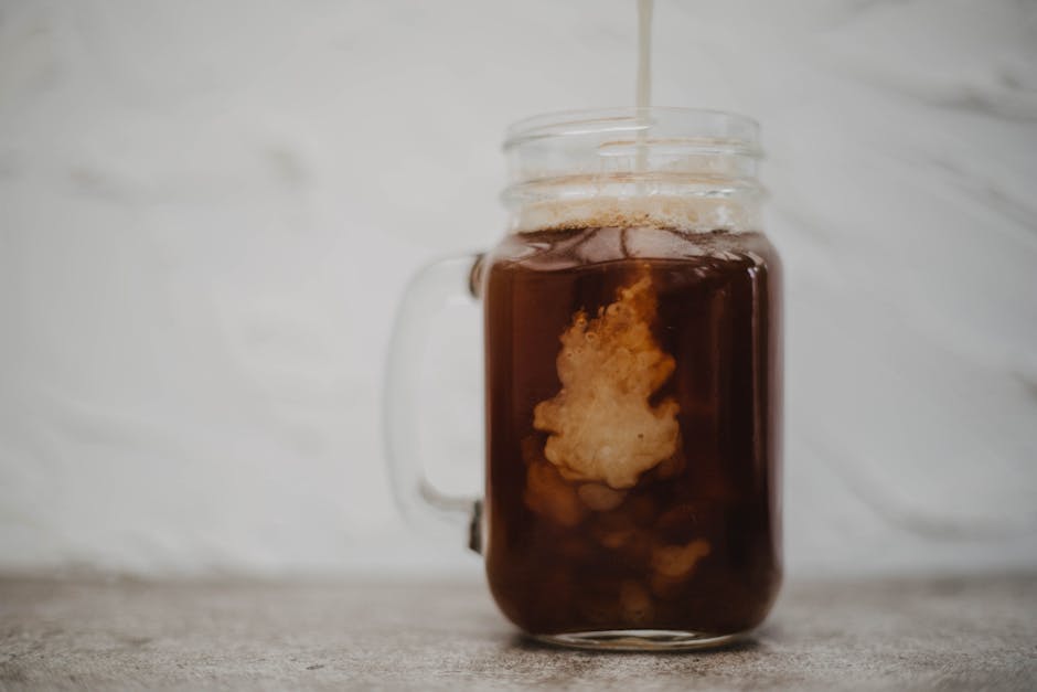 Cream swirling into cold brew coffee in a mason jar