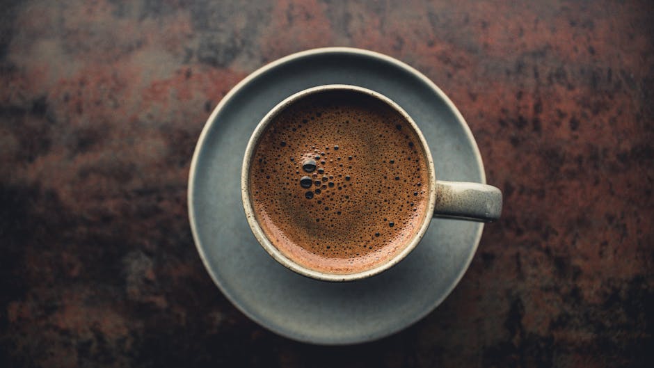 Top view of a hot espresso in a rustic ceramic mug on a dark textured surface