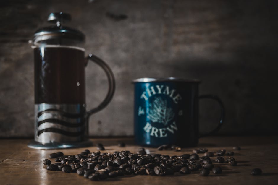 A cozy French press brewing setup with a mug and coffee beans arranged on a warm wooden table