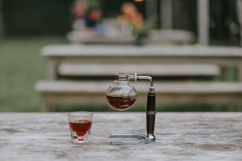 Close-up of a siphon coffee maker and coffee cup on a wooden table